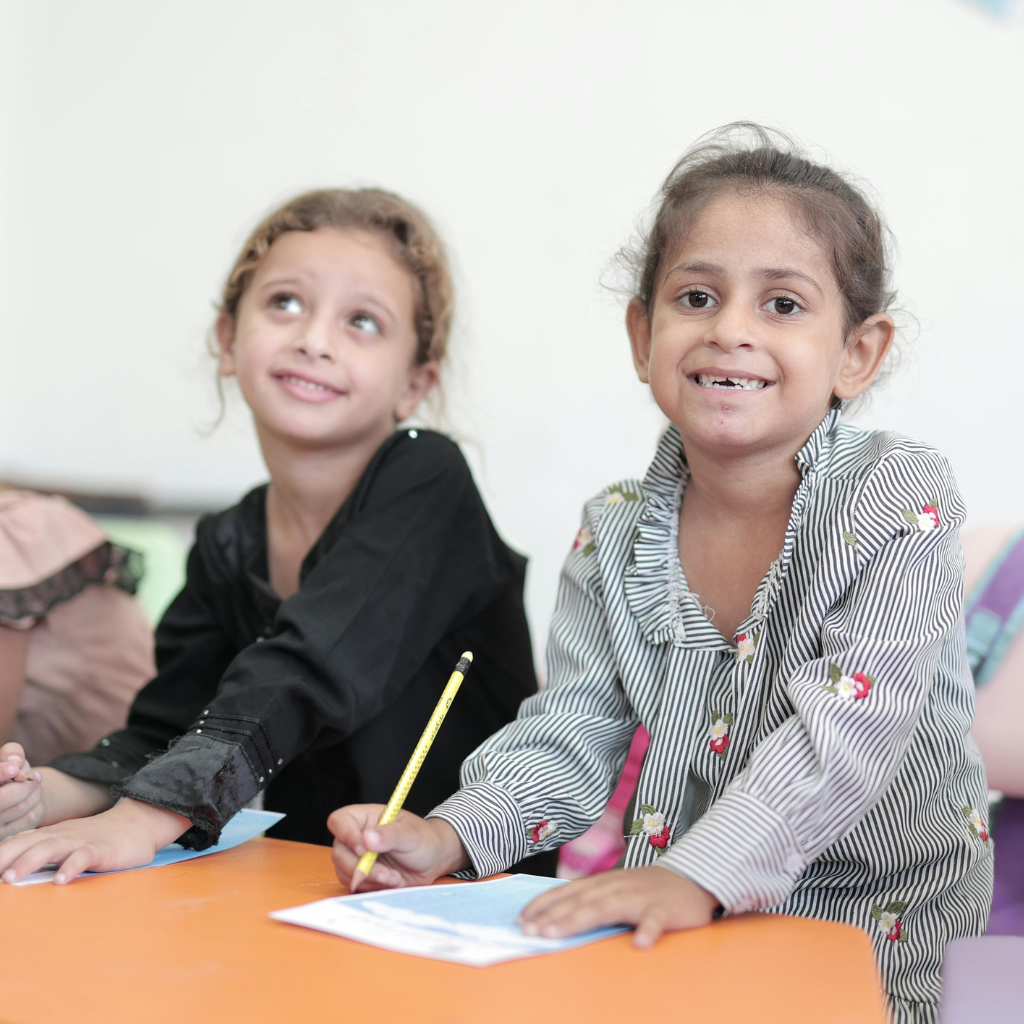 About Us children smiling and writing - Empowerment